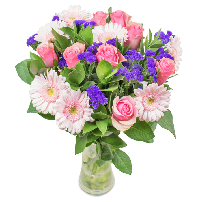 Set against a spotless white background reminiscent of Mitcham's airy garden rooms, this sophisticated bouquet displays about seven to nine pink roses-some in tight, elegant buds, others unfurling soft petals in classic, swirling shapes. They're surrounded by five to seven pale pink gerbera daisies, their wide, welcoming faces and silvery centers reminiscent of spring blooms beside the paths of Ravensbury Park. Threads of vivid purple statice weave through the arrangement, their rich colour deepening the palette and introducing playful texture. At the base, lush greenery provides a foundation of cool-toned leaves, echoing the thriving plants along the River Wandle. The clear glass vase reveals fresh-cut stems and pure water, symbolizing freshness and the care of same-day delivery from local Mitcham florists. Versatile and beautifully balanced, this arrangement is perfect for personal milestones-birthdays, anniversaries, or heartfelt thank-yous-each element thoughtfully chosen to reflect the welcoming spirit of the Mitcham community and the abundant joys of its green spaces.